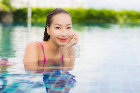 Téléchargez les photos : Portrait belle jeune femme asiatique se détendre profiter autour de la piscine extérieure en vacances - en image libre de droit
