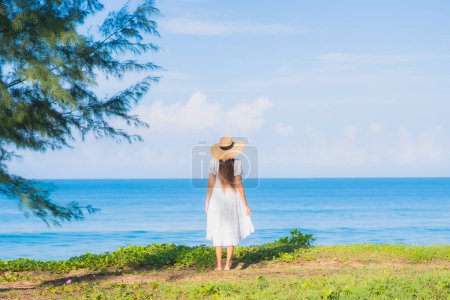 Téléchargez les photos : Portrait belle jeune femme asiatique se détendre sourire autour de la plage mer océan avec ciel bleu nuage blanc pour les vacances de voyage - en image libre de droit