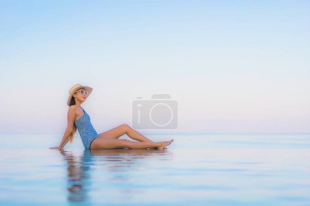 Téléchargez les photos : Portrait belle jeune femme asiatique relax sourire loisirs autour de la piscine extérieure presque plage de la mer en vacances Voyage - en image libre de droit