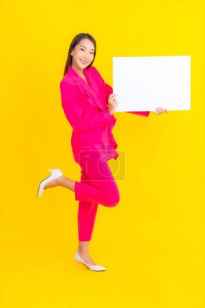 Photo for Portrait beautiful young asian woman with empty white billboard on yellow isolated background - Royalty Free Image