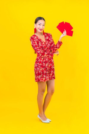 Téléchargez les photos : Portrait belle jeune femme asiatique avec des enveloppes rouges sur fond jaune - en image libre de droit