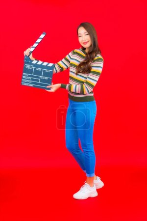 Foto de Retrato hermosa joven asiática mujer con película pizarra corte en rojo aislado fondo - Imagen libre de derechos