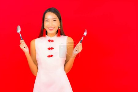 Foto de Retrato hermosa joven asiática mujer con cuchara y tenedor en aislado rojo fondo - Imagen libre de derechos