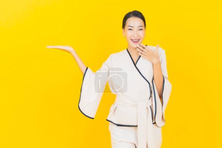 Téléchargez les photos : Portrait belle jeune femme d'affaires asiatique avec sourire et action fond jaune - en image libre de droit