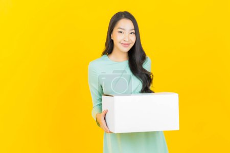 Foto de Retrato hermosa joven mujer asiática con caja listo para el envío en el fondo de color - Imagen libre de derechos