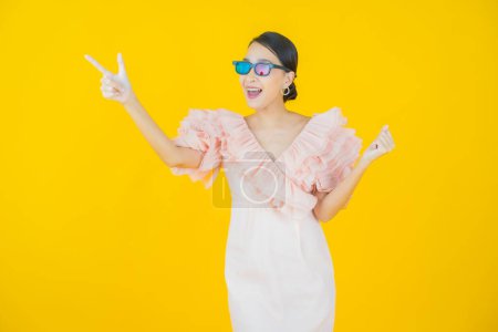 Téléchargez les photos : Portrait belle jeune femme asiatique porter des lunettes 3D sur fond de couleur - en image libre de droit