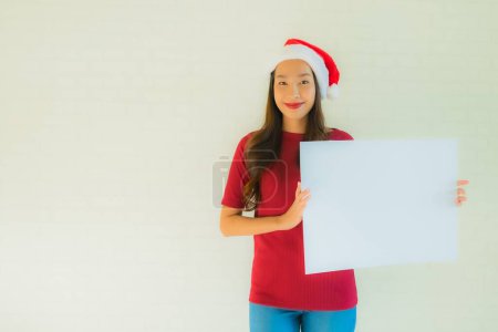 Foto de Retrato hermosa joven asiático mujeres desgaste santa navidad sombrero mostrar blanco blanco tarjeta de la junta con espacio de copia - Imagen libre de derechos