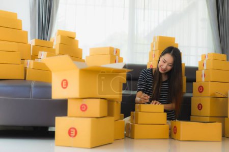 Photo for Portrait beautiful young asian woman with container cardboard parcel box packaging prepare for shipping for customer online shopping in living room - Royalty Free Image