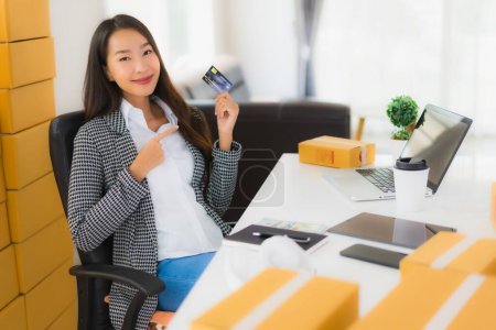 Foto de Retrato hermosa mujer asiática joven trabajo desde casa con tarjeta de crédito y caja de cartón listo para el envío de compras en línea - Imagen libre de derechos