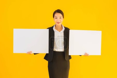 Photo for Beautiful portrait young asian woman show empty blank white board on yellow isolated background - Royalty Free Image