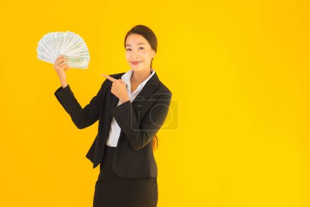 Photo for Beautiful portrait young asian woman with a lot of monet cash on yellow isolated background - Royalty Free Image