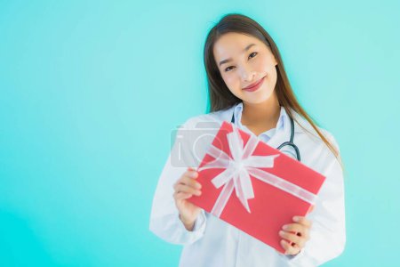 Foto de Retrato hermosa joven asiática médico mujer con caja de regalo en azul aislado fondo - Imagen libre de derechos