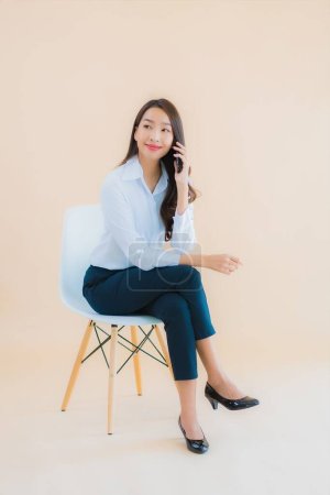 Foto de Retrato hermosa joven negocio asiático mujer sentarse en la silla con el ordenador portátil o teléfono inteligente para el trabajo - Imagen libre de derechos