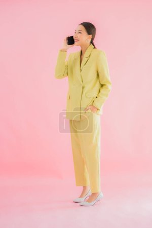 Téléchargez les photos : Portrait belle jeune femme d'affaires asiatique utiliser téléphone portable intelligent avec tasse de café sur fond de couleur - en image libre de droit