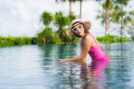 Téléchargez les photos : Portrait belle jeune femme asiatique se détendre profiter autour de la piscine extérieure en vacances - en image libre de droit