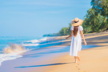Téléchargez les photos : Portrait belle jeune femme asiatique se détendre sourire loisirs autour de la mer plage océan avec nuage blanc sur ciel bleu en vacances Voyage - en image libre de droit