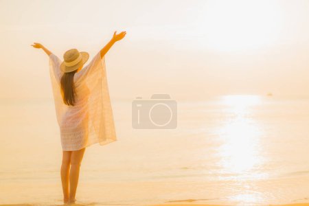 Foto de Retrato hermosa joven asiática mujer relajarse sonrisa ocio alrededor al aire libre mar playa océano al atardecer tiempo para vacaciones - Imagen libre de derechos