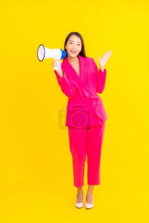 Téléchargez les photos : Portrait belle jeune femme asiatique avec mégaphone pour la communication sur fond jaune isolé - en image libre de droit