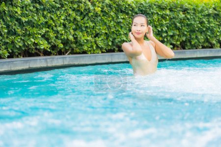 Foto de Retrato hermosa joven asiática mujer relajarse sonrisa ocio en vacaciones alrededor de la piscina en resort hotel - Imagen libre de derechos