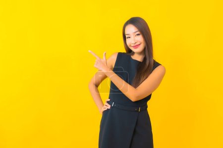 Téléchargez les photos : Portrait belle jeune femme d'affaires asiatique sourire avec action sur fond de couleur jaune - en image libre de droit