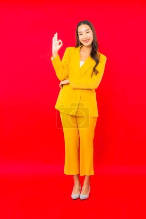 Téléchargez les photos : Portrait belle jeune entreprise asiatique femme sourire avec action sur fond rouge isolé - en image libre de droit