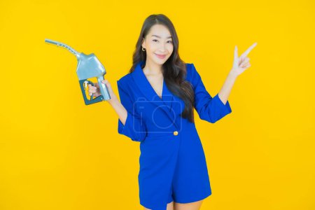 Téléchargez les photos : Portrait belle jeune asiatique femme querelle pompe à essence sur fond de couleur - en image libre de droit