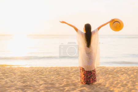 Foto de Retrato hermosa joven asiático mujeres feliz sonrisa relajarse alrededor de playa mar océano al atardecer o amanecer tiempo para vacaciones de viaje - Imagen libre de derechos
