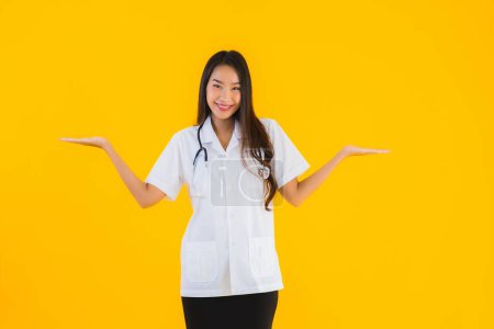 Foto de Retrato hermosa joven asiática médico mujer sonrisa feliz trabajo en hospital y clínica en amarillo aislado fondo - Imagen libre de derechos