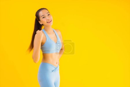 Téléchargez les photos : Portrait belle jeune femme de sport asiatique avec des vêtements de sport prêt pour l'exercice sur fond jaune isolé - en image libre de droit