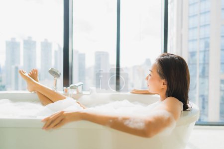 Foto de Retrato hermosa joven mujer asiática relajarse y ocio en la decoración de la bañera en el interior del baño - Imagen libre de derechos