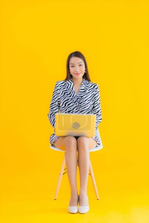 Photo for Portrait beautiful young asian woman use laptop computer on yellow isolated background - Royalty Free Image
