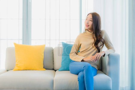 Téléchargez les photos : Portrait belle jeune femme asiatique se détendre loisirs profiter sur canapé dans le salon espace intérieur - en image libre de droit
