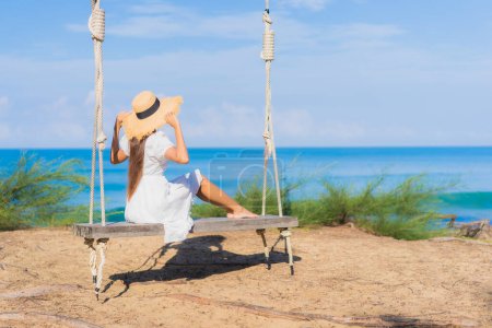 Foto de Retrato hermosa joven asiático mujer relax sonrisa en swing alrededor playa mar océano para naturaleza viaje en vacaciones - Imagen libre de derechos
