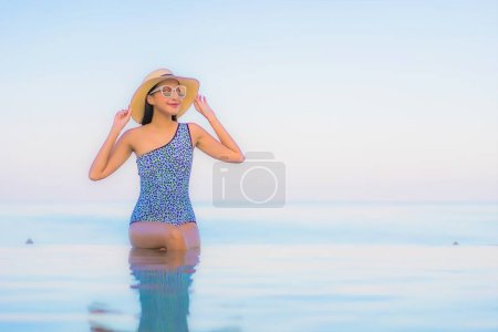 Téléchargez les photos : Portrait belle jeune femme asiatique relax sourire loisirs autour de la piscine extérieure presque plage de la mer en vacances Voyage - en image libre de droit