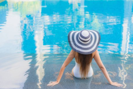 Foto de Retrato hermosa joven mujer asiática relajarse sonrisa alrededor de la piscina al aire libre en el complejo hotelero casi mar playa océano - Imagen libre de derechos