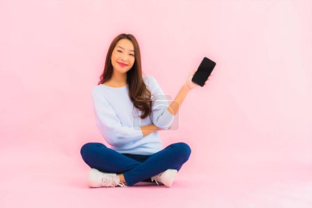 Téléchargez les photos : Portrait belle jeune femme asiatique utiliser téléphone mobile intelligent sur fond isolé couleur rose - en image libre de droit