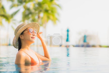 Foto de Retrato hermosa joven asiática mujer relajarse sonrisa ocio alrededor al aire libre piscina casi mar playa océano al atardecer tiempo para vacaciones - Imagen libre de derechos