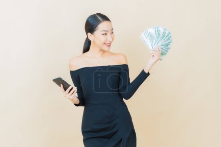 Foto de Retrato hermosa joven asiática mujer sonrisa con un montón de dinero en efectivo y dinero en color de fondo - Imagen libre de derechos