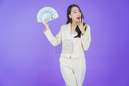 Téléchargez les photos : Portrait belle jeune femme asiatique sourire avec beaucoup d'argent et d'argent sur fond de couleur - en image libre de droit