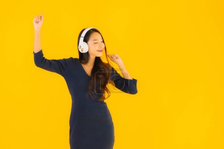 Photo for Portrait beautiful young asian woman with headphone for listen music on yellow isolated background - Royalty Free Image