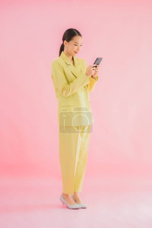 Téléchargez les photos : Portrait belle jeune femme d'affaires asiatique utiliser téléphone portable intelligent avec tasse de café sur fond de couleur - en image libre de droit