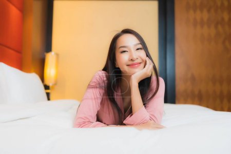 Foto de Retrato hermosa joven asiática mujer relajarse sonrisa feliz en la cama en el interior del dormitorio - Imagen libre de derechos