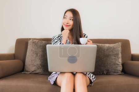 Photo for Portrait beautiful young asian woman use computer laptop on sofa in living room interior area - Royalty Free Image