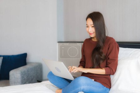 Foto de Retrato hermosa joven mujer asiática uso de ordenador portátil en la cama en el interior del dormitorio - Imagen libre de derechos