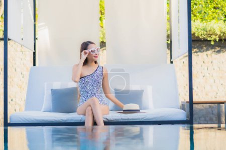 Foto de Retrato hermosa joven mujer asiática relajarse sonrisa ocio alrededor de la piscina al aire libre casi playa de mar en vacaciones de viaje - Imagen libre de derechos
