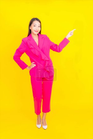 Téléchargez les photos : Portrait belle jeune femme asiatique sourire en action sur fond de couleur jaune - en image libre de droit