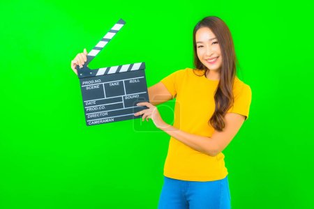 Téléchargez les photos : Portrait belle jeune femme asiatique avec film clapper sur fond vert isolé - en image libre de droit