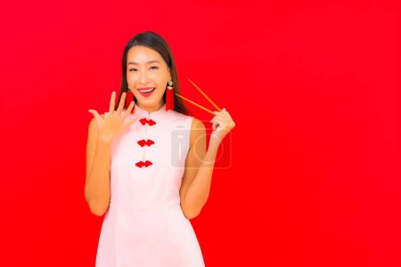 Foto de Retrato hermosa joven asiática mujer con palillo en rojo aislado fondo - Imagen libre de derechos