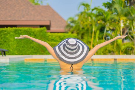 Foto de Retrato hermosa joven asiática mujer relajarse sonrisa disfrutar de ocio alrededor de la piscina en resort hotel de vacaciones - Imagen libre de derechos