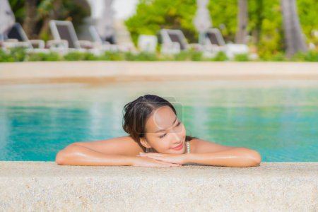 Téléchargez les photos : Portrait belle jeune femme asiatique relax sourire loisirs autour de la piscine extérieure avec océan de mer en vacances Voyage - en image libre de droit
